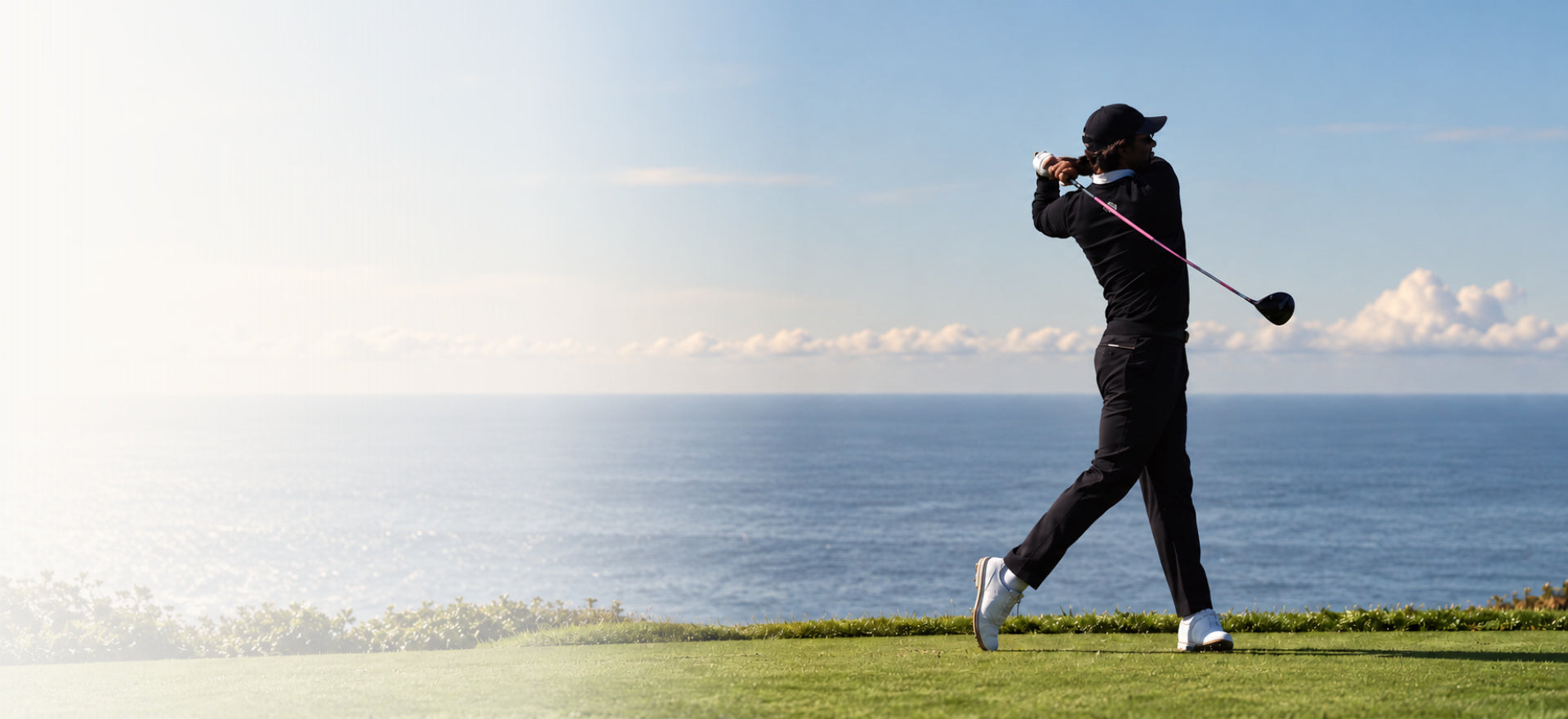 Golfer mid-swing on a course by the ocean